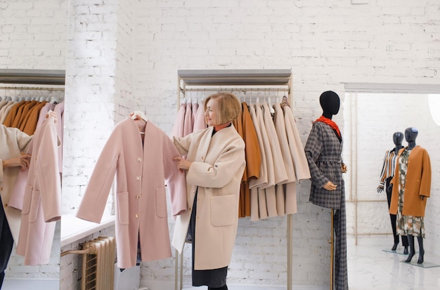 Een oudere vrouw in een kledingwinkel kiest een jas Winkelen kleding kopen