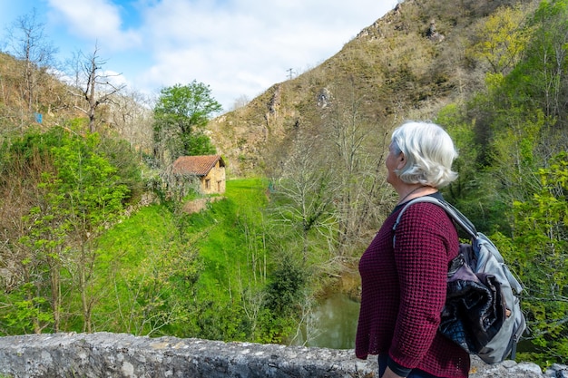 Een oudere vrouw loopt over de brug op het pad tussen El Tornin a la Olla de San Vicente in de buurt van Cangas de Onis Asturias, Spanje