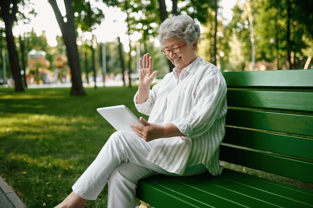 Een oudere vrouw met een bril die een laptop op de bank gebruikt