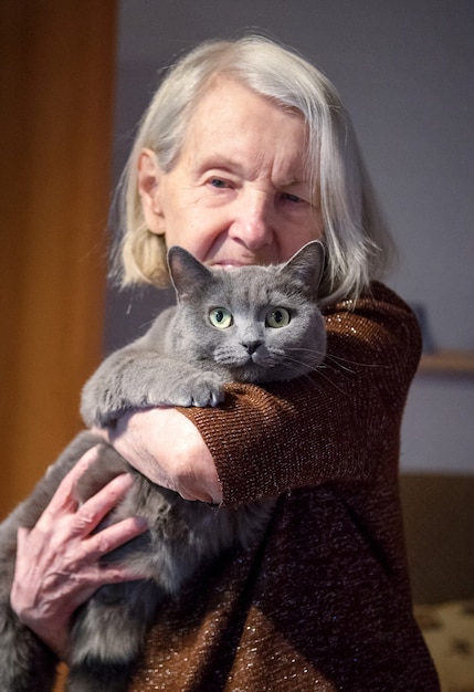 Een oudere vrouw met een kat kijkt naar de camera.