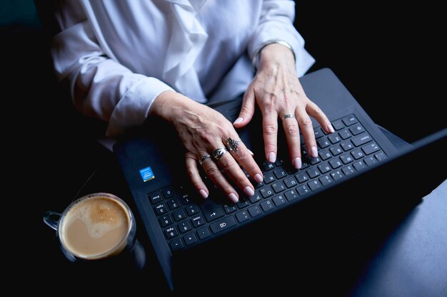 een oudere vrouw werkt in een café bij een laptop