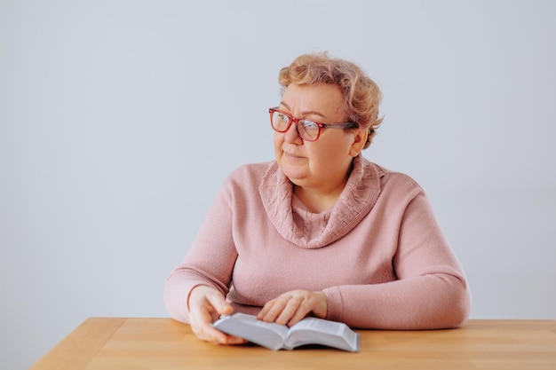 Een overgewicht vrouw zit in haar gezellige huis een boek te lezen en draagt een bril die op de bri rust
