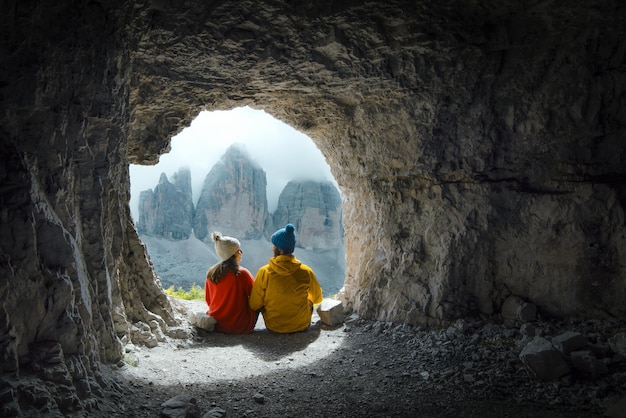 Een paar bergbeklimmers observeren het uitzicht op tre cime di lavadero vanuit een grot in italië