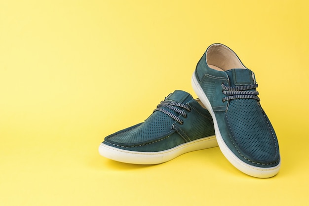 Een paar blauwe zomerschoenen voor heren op een gele achtergrond. Comfortabele zomerschoenen voor heren.