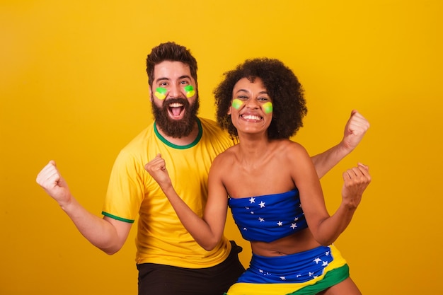 Een paar braziliaanse voetbalfans gekleed in de kleuren van brazilië zwarte vrouw blanke man Vieren het team geluk wensen