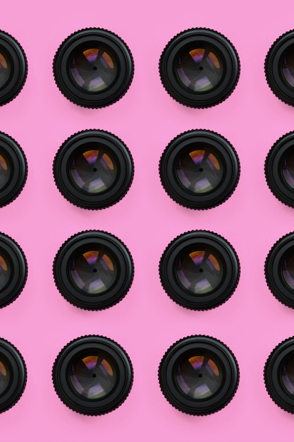 Een paar cameralenzen met een gesloten opening liggen op textuurachtergrond van de roze kleur van de manierpastelkleur