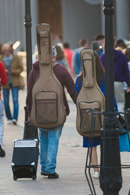 Een paar jonge straatmuzikanten met gitaren op hun rug die over straat lopen