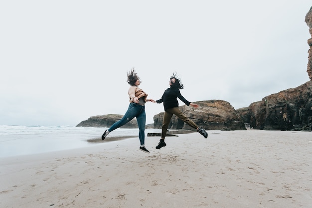 Een paar jonge vrouwen springen in een wild strand met vrijheid tijdens een zonnige dag