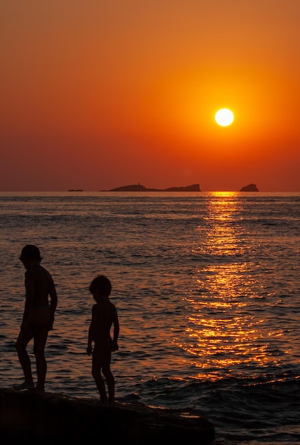 een paar kinderen spelen op een strand bij zonsondergang