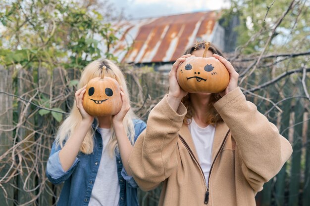 Een paar lachende tieners met halloween-pompoenen die plezier hebben