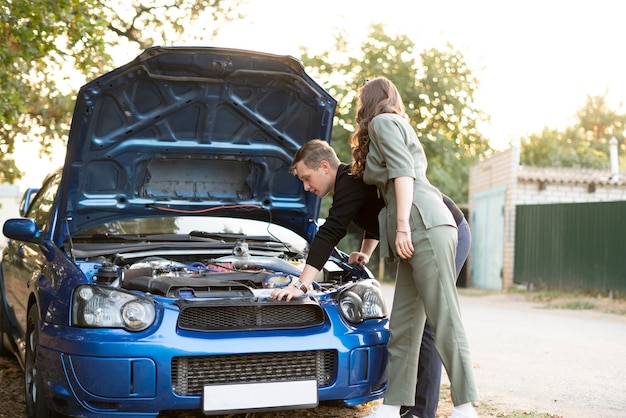 Een paar mannen en vrouwen hebben wat autoproblemen tijdens het reizen, reparatie motorcontrole engine