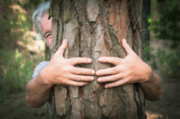 Een paar menselijke handen knuffelen een boom in het bos liefde voor het buitenleven en de natuur earth day concept Een oude man verstopt zich voor de stam Mensen redden de planeet van ontbossing