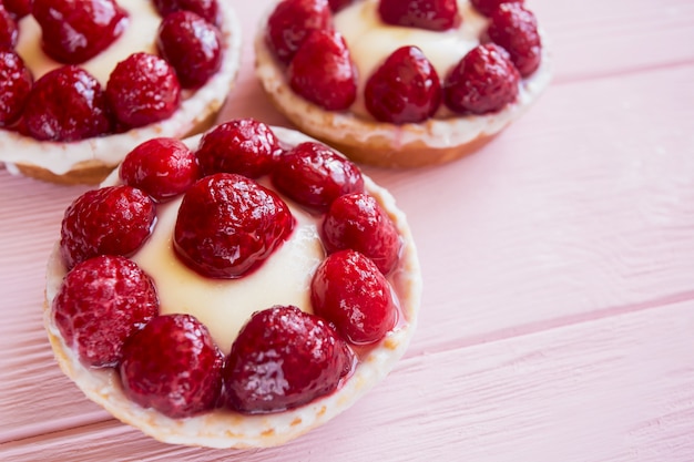 Een paar panna cotta gebakjes met room en frambozen close-up op een delicate roze houten achtergrond met vrije ruimte