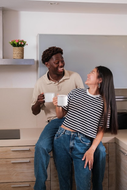 Een paar van verschillende afkomst met een kopje koffie thuis zittend op het aanrecht Concept lifestyle ontbijt samen