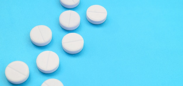 Een paar witte tabletten liggen op een helder blauw oppervlak. beeld op medische en farmaceutische onderwerpen