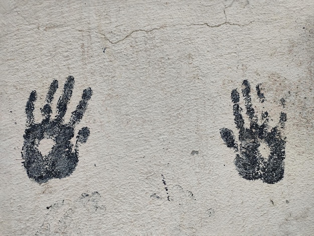 Foto een paar zwarte afdrukken van de handpalmen van kinderen op een grijze betonnen muur.