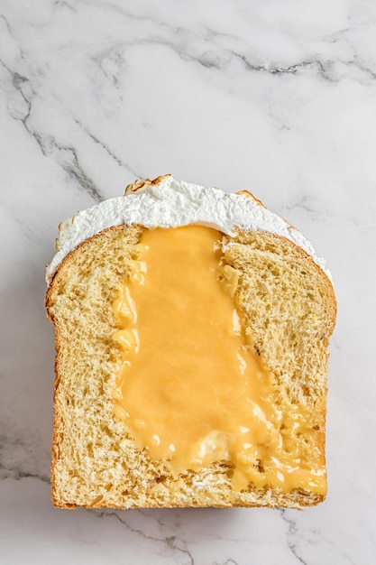 Een paascake met meringue in de bovenkant in tweeën gesneden met vloeibare vulling van citroengestremde melk op een lichtgrijze marmeren achtergrond