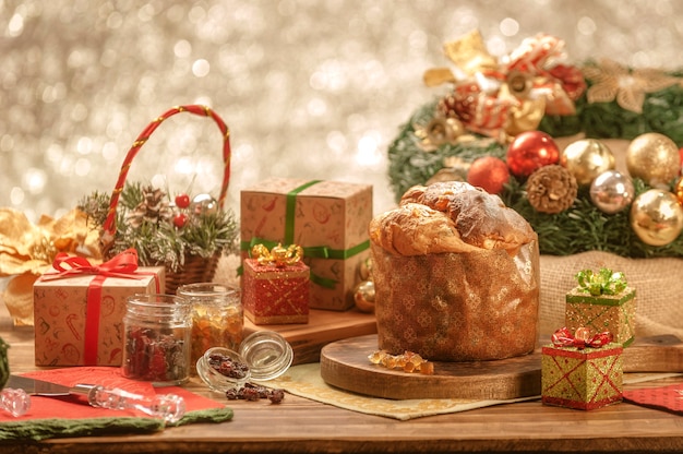 Een panettone en gekonfijte fruitblokjes op houten snijplank met kerstversieringen