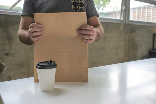 Een papieren kopje koffie en bezorging of afhaalzak met eten. Voor mock-up.