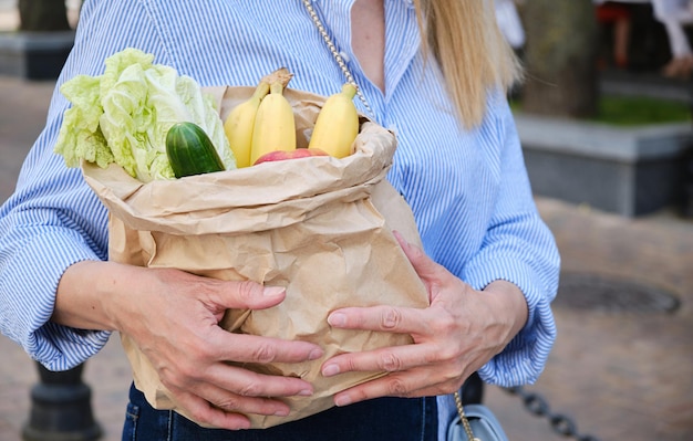 Een papieren zak met groenten en fruit in vrouwelijke handen