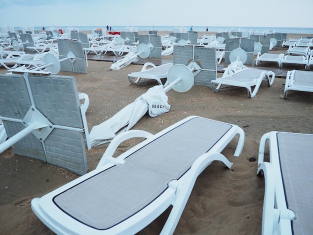 Een parasol lag opgevouwen op een zandstrand na een storm op zee aan het einde van het strandseizoen