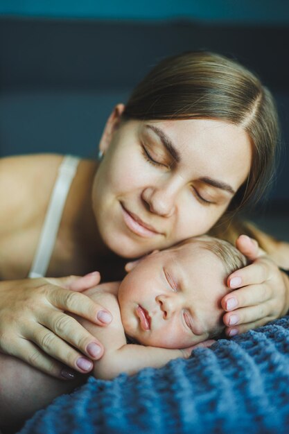 Een pasgeboren baby met zijn moeder ligt op een grijze zachte deken een moeder knuffelt haar pasgeborene