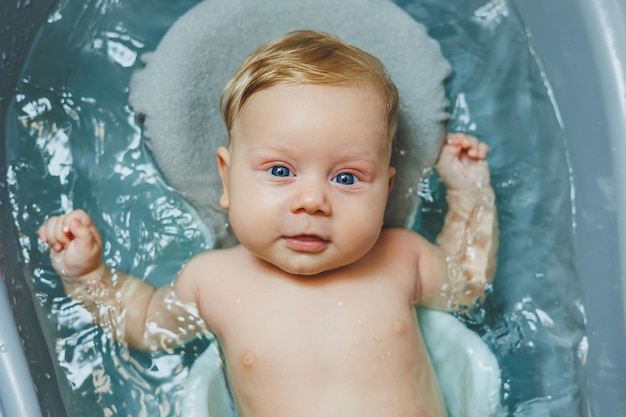 Een pasgeboren baby neemt een bad, ouders baden het kind, de pasgeborene wordt gewassen, de pas geborene glimlacht, de baby wordt verzorgd.