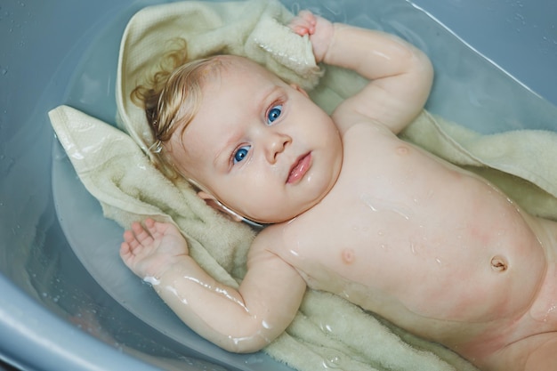 Een pasgeboren jongen van vijf maanden badt in een badkuip.