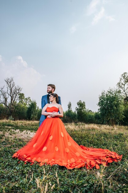 Foto een pasgetrouwd stel omhelst elkaar op het veld tegen de lucht.