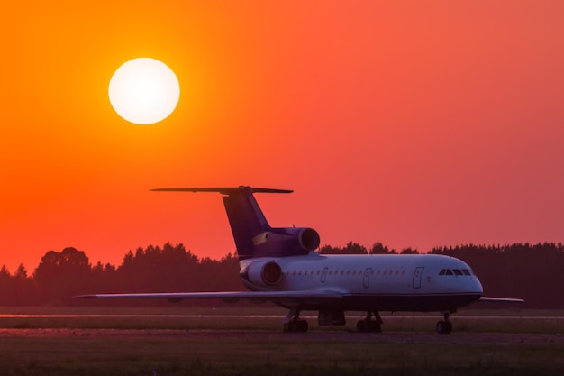 Een passagiersvliegtuig op de taxibaan van de belangrijkste luchthaven tegen de achtergrond van een schilderachtige zonsondergang