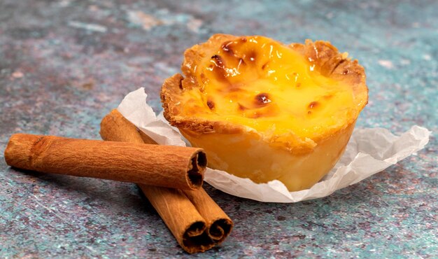 Een pastel de nata of Portugese eiertart en kaneelstokjes pastel de belm is een kleine taart met een