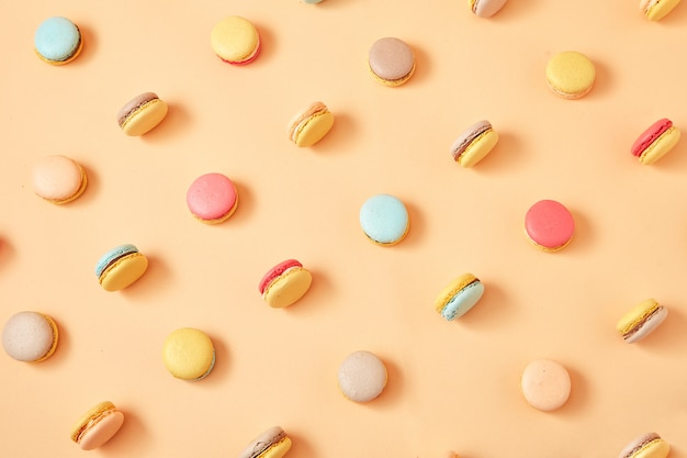 een patroon van kleurrijke Franse koekjes macarons op gele perzik achtergrond
