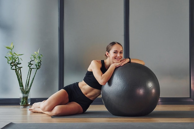 Een pauze nemen Jonge vrouw in sportieve kleding en met een slank lichaam heeft een fitness-yogadag binnenshuis