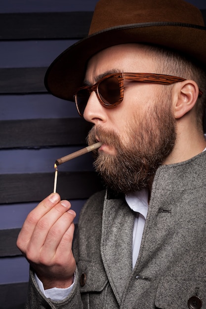 Foto een pauze nemen om te roken. knappe jongeman met zonnebril steekt een sigaret op