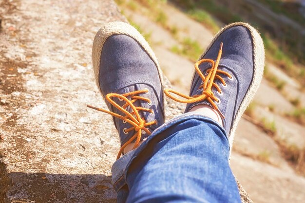 Een persoon die een blauwe spijkerbroek draagt en een paar blauwe schoenen met oranje veters