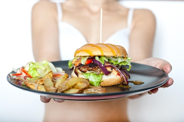 Een persoon die een bord met een burger en friet vasthoudt.