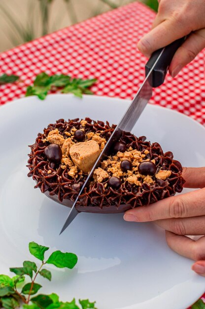 Een persoon die een chocolade pindakaasbeker snijdt met een mes.