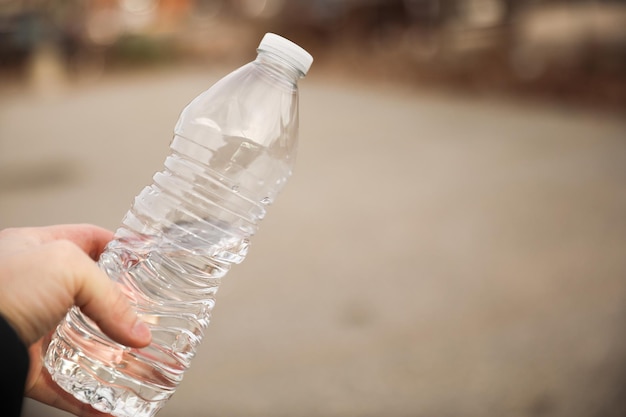 Een persoon die een fles water in zijn hand houdt.