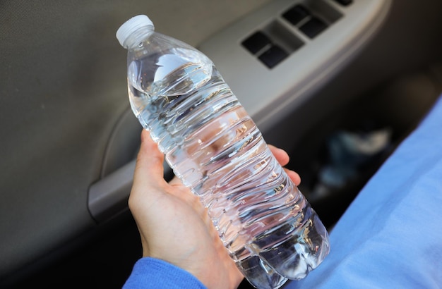 Een persoon die een fles water in zijn hand houdt