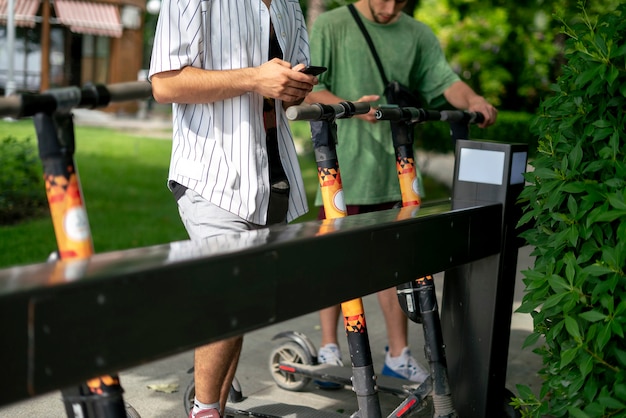 Een persoon die een huurscooter neemt om zich in de stadsstraat te verplaatsen, een ecologiemodus, met behulp van een smartphone-app