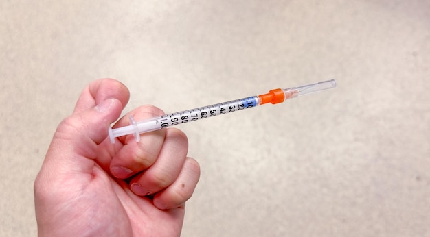 Een persoon die een injectiespuit vasthoudt met het woord " erop.