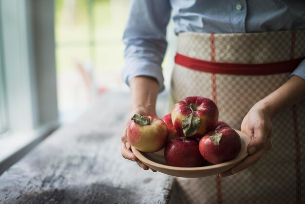 Een persoon die een kom biologische appels met een rode schil vasthoudt