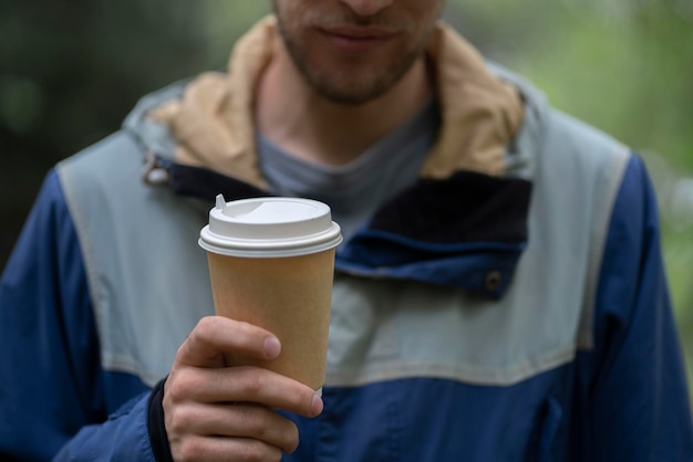 Een persoon die een papieren beker met warme drank vasthoudt