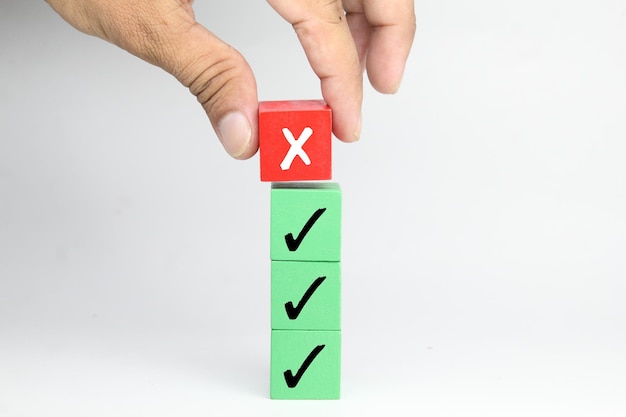 Een persoon die een rode x op een groene kubus plaatst met een groen vak waarop een x staat.