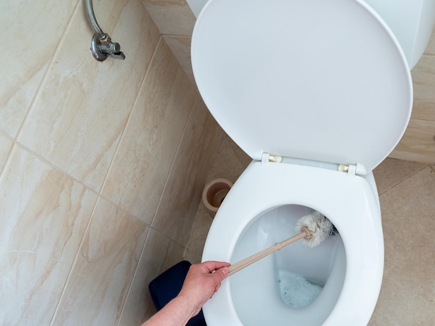 Een persoon die een toilet schoonmaakt met een borstel