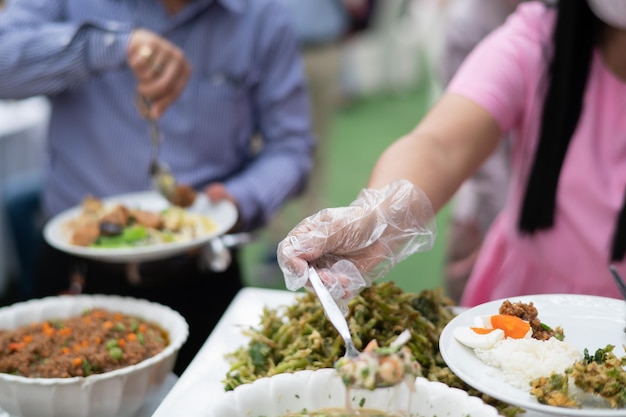 Een persoon die handschoenen draagt, voedsel scheppen, catering, etenstijd, coronavirusziekte voorkomen (covid 19)