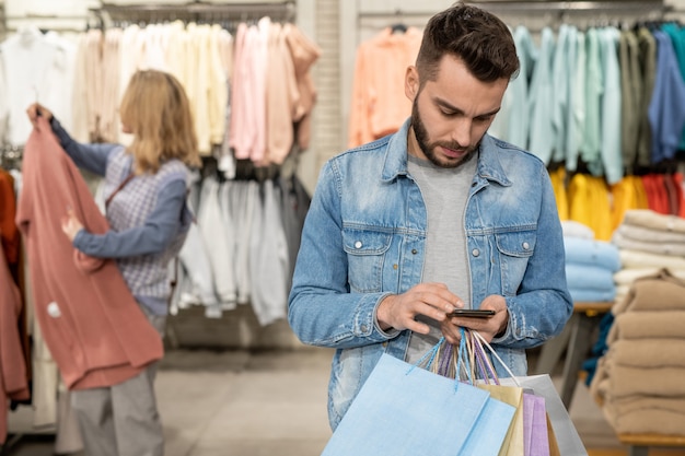 Een persoon die naar de telefoon kijkt in een kledingwinkel