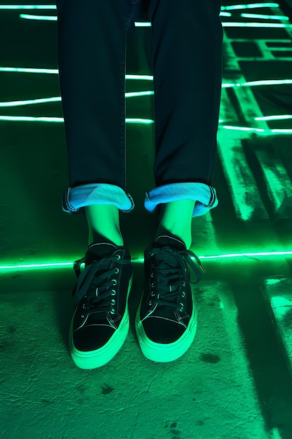 Een persoon die zwarte en groene sneakers draagt en op een groene vloer staat