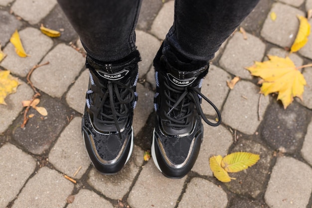 Een persoon die zwarte schoenen draagt met het woord adidas op de zijkant.