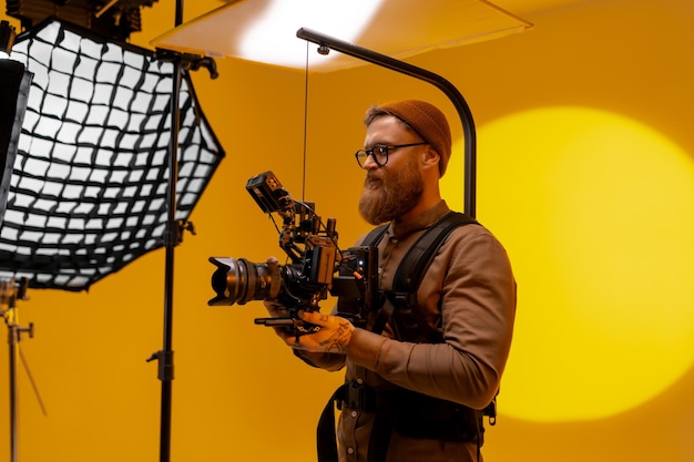 Foto een persoon gebruikt een camera voor een gele achtergrond terwijl hij video opneemt op een evenement